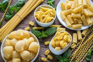 Various types of pasta on the wooden background photo