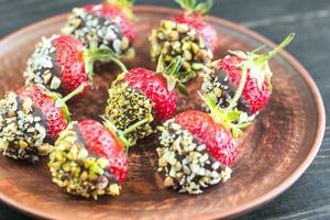 Fresh strawberries covered with dark chocolate and nuts photo