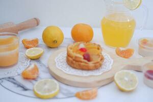 Homemade lemon tart with fresh fruit and orange juice on white background photo