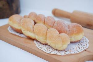 Bread donuts on the wooden table with wooden rolling pin. photo