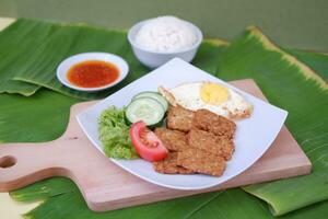 Fried tempeh cutlet with rice and fried egg on white plate photo