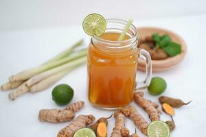 Fresh ginger and lemon juice in a glass jar with ginger roots on white background. photo