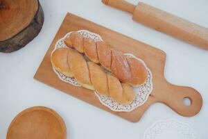 Bread donuts on the wooden table with wooden rolling pin. photo