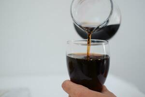 Pouring cola from a jug into a glass on a white background photo