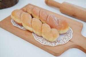 Bread donuts on the wooden table with wooden rolling pin. photo