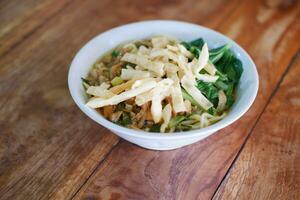 Fried noodle in white bowl on wooden table photo
