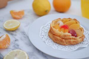 Fruit tart on a white plate with lemons and tangerines photo