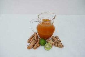 Ginger juice in a jug and fresh ginger on a white background photo