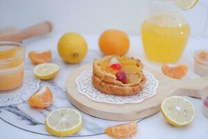 Homemade lemon tart with fresh fruit and orange juice on white background photo