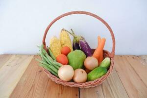 Vegetables in a basket on wooden background. Healthy food concept. photo