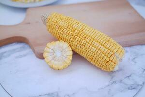 Corn on the cob and corn kernels on a white plate on a white background photo