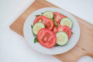 Cucumber and tomato slices on a plate on a white background photo