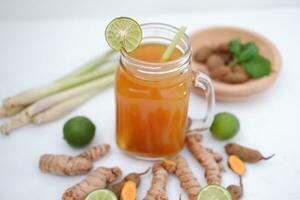 Fresh ginger and lemon juice in a glass jar with ginger roots on white background. photo