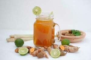 Fresh ginger and lemon juice in a glass jar with ginger roots on white background. photo