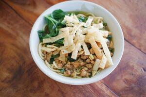 Fried noodle in white bowl on wooden table photo