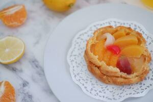 Fruit tart on a white plate with lemons and tangerines photo