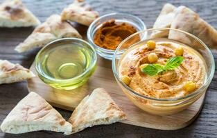 un plato de hummus con rodajas de pita foto