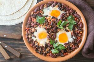 Bowl of chipotle bean chili with baked eggs photo