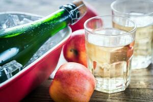 Bottle and two glasses of cider on the wooden background photo