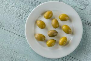 Green olives on the white plate photo