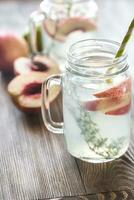 Glass jar of lime water with slices of peach photo