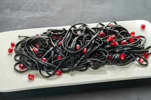 Black pasta with pomegranate seeds photo