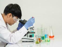 Portrait asian man student scientist Wearing a doctor gown in the lab looking hand at chemist. caused by mixing reagents in scientific research laboratories with test tubes and microscope on the table photo