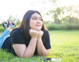 retrato joven mujer asiático gordito linda hermosa uno persona vestir negro camisa Mira mano participación utilizando inteligente teléfono en jardín parque al aire libre noche luz de sol Fresco sonriente alegre contento relajarse verano día foto