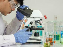 Portrait asian man student scientist Wearing a doctor gown in the lab looking hand at chemist. caused by mixing reagents in scientific research laboratories with test tubes and microscope on the table photo