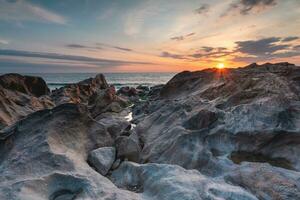 puesta de sol a el rocoso playa a vila estrella nueva Delaware gaia, Portugal. foto