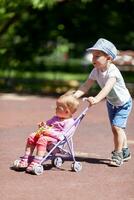 Boy pushing sister in a stroller photo