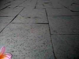 Beautiful pink frangipani flower on the ground, Floor with exotic natural stone. photo