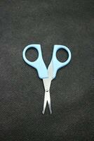 Small blue scissors on a black background photo