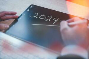 Concept for financial planning and reminder for 2024. man using digital tablet or smartphone working with calendar 2024, business planning marketing and investment photo