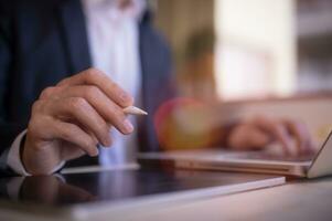 business and technology, businessman using computer laptop and tablet holding pen pointing presenting business data marketing report photo