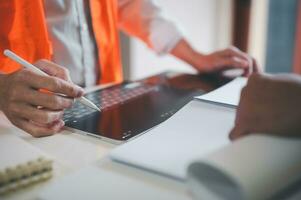 engineer or foreman using tablet and pen presenting or discussing project plan with co worker photo