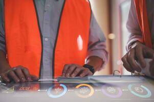 engineer or foreman using tablet and pen presenting virtual chart circuit diagram on table at site photo