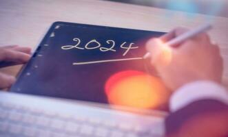 concepto para financiero planificación y recordatorio para 2024. hombre utilizando digital tableta o teléfono inteligente trabajando con calendario 2024, negocio planificación márketing y inversión foto