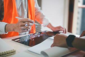 engineer or foreman using tablet and pen presenting virtual chart circuit diagram on table at site photo