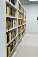 a large number of bookshelves with books. White bookshelves in the library, on which there are many books. photo