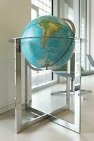 A large globe on a metal stand is in the room. South America on the globe. The South Pole. photo