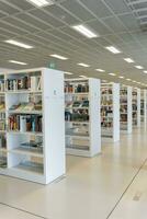 A large number of bookshelves with books. White bookshelves in the library, on which there are many books. photo