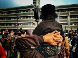 29 july 2023. Back view of a father hand hold his son so high to give a good view for him to see the  Asian Africa Festival at Bandung City West Java Indonesia. photo