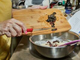 cocinero agrega aceitunas a el tarta masa en el cuenco foto