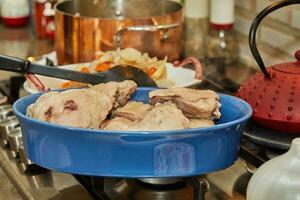 Chef pours chicken broth from copper pot into dish of chicken legs photo