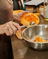 cocinero cortes melón pelotas con especial cuchara en cocina foto