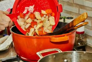 cocinero agrega hervido vegetales a pollo piernas frito en pan foto