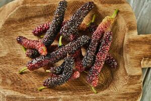 Afghan mulberry black and red on wooden scoop on gray wooden background photo