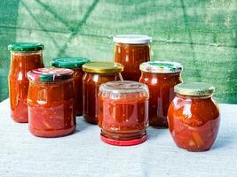 tradicional húngaro hecho en casa lecho en vaso frascos. Preservado Tomates y pimientos con especias foto