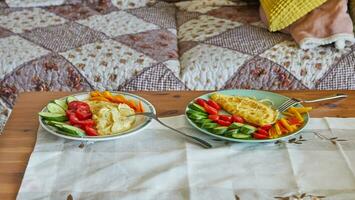 Morning healthy breakfast of scrambled eggs with parmesan cheese, cucumbers, cherry tomatoes and sweet peppers on the coffee table in front of the sofa photo